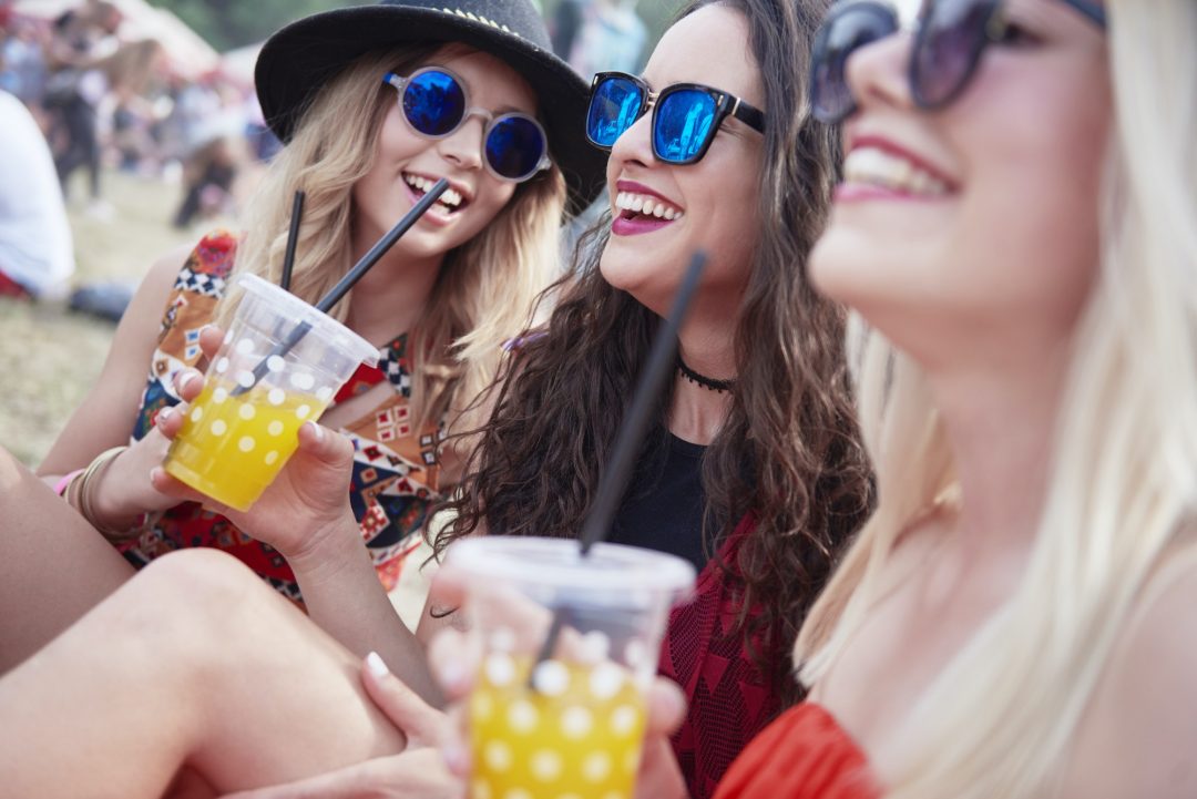 friends-drinking-juice-and-sitting-on-meadow-during-music-festival.jpg