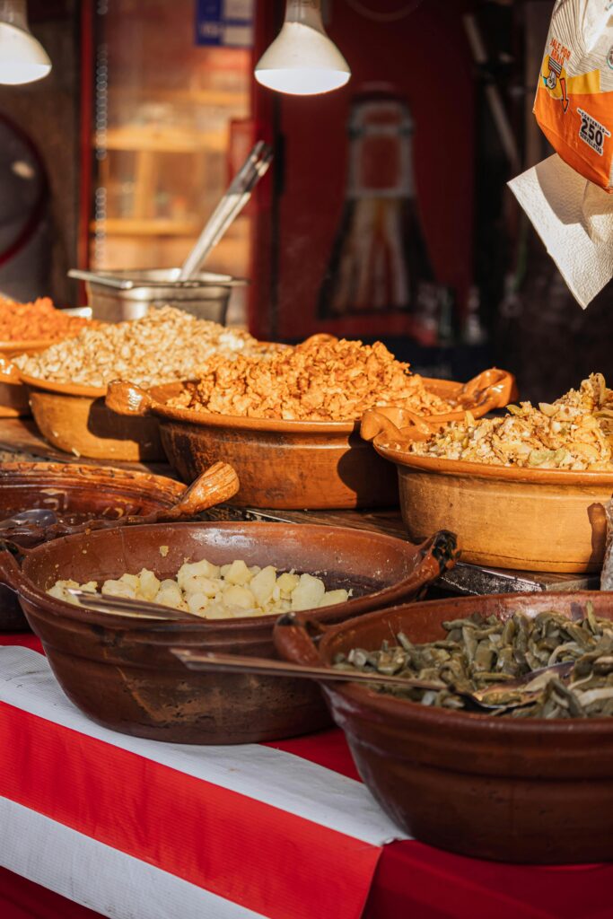A colorful display of diverse traditional street food in pottery bowls, ready to be served.