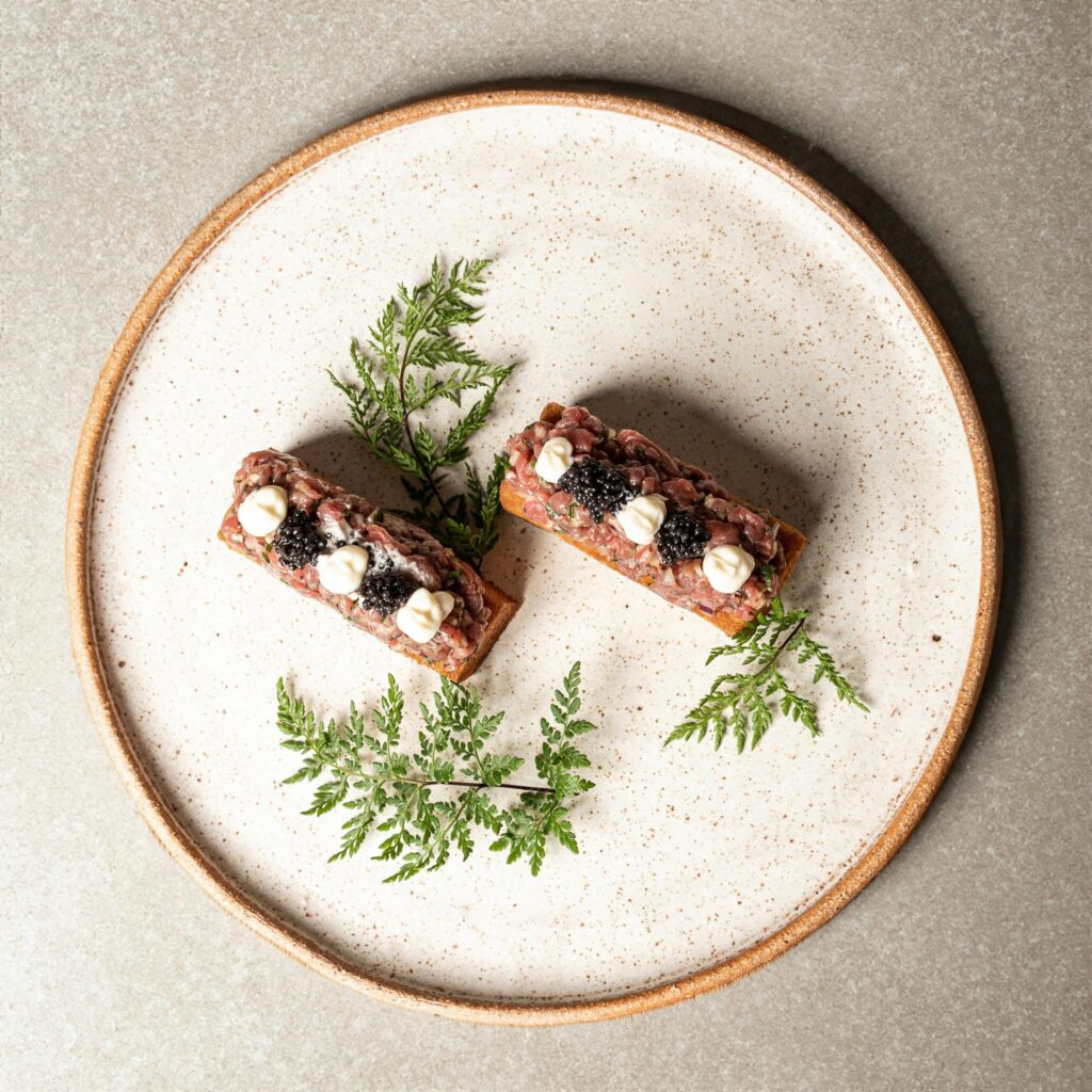 Elegant gourmet appetizers garnished on a rustic ceramic plate with green herbs.