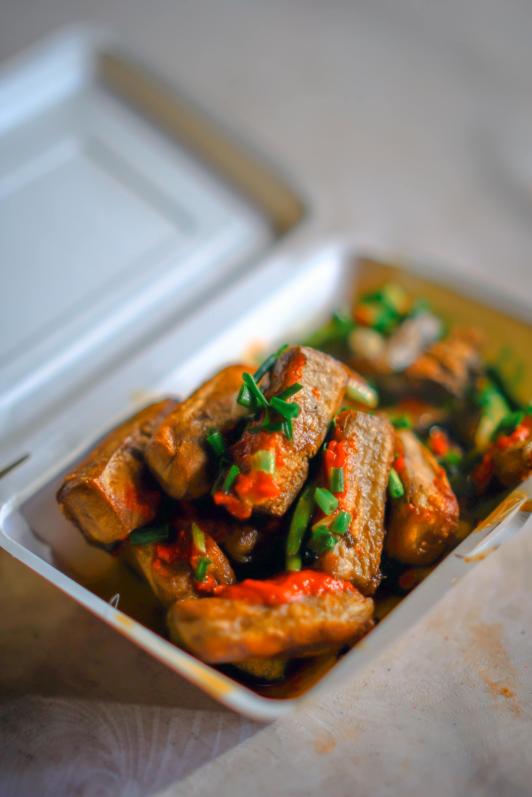 Tasty grilled ribs with sauce and herbs in a takeout box, ready to enjoy.