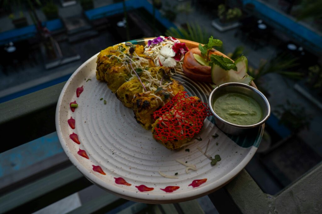 Appetizing Indian grilled tikka platter with chutney and fresh garnishes on a stylish plate.