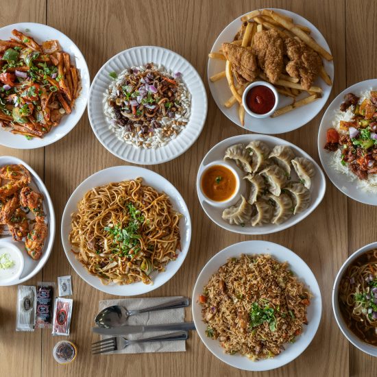Top view of various Asian and Western cuisine dishes on a wooden table.
