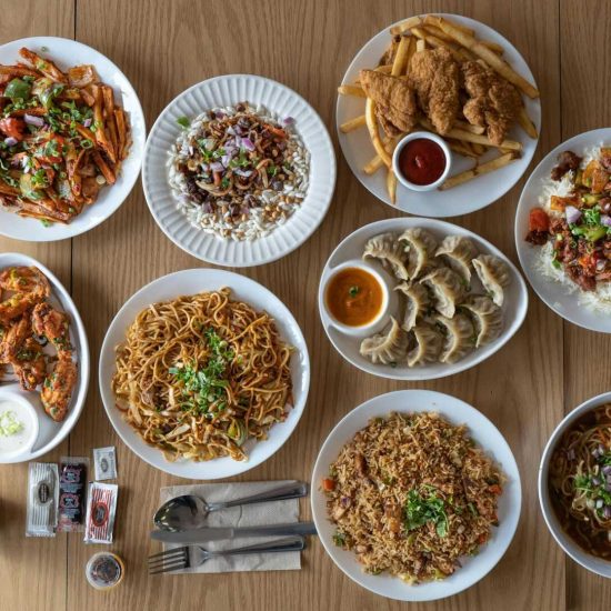Top view of various Asian and Western cuisine dishes on a wooden table.